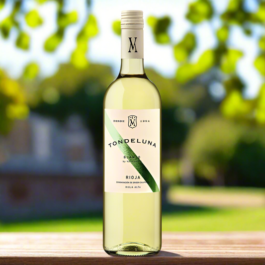 Bottle of spanish white rioja. Cream label with a green line through it. Set on a bench in a garden