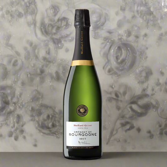 A bottle of cremant with a white label set against a grey floral wall paper
